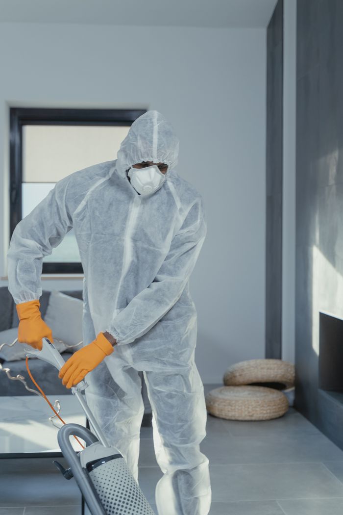 project-01-b A person in personal protective equipment vacuuming indoors, ensuring a thorough clean.